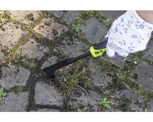 O persoană îndepărtează buruienile dintre pietrele de pavaj cu o racletă pentru rosturi for_q.