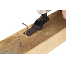 Unealtă multifuncțională cu pânză de ferăstrău taie un cui într-o grindă de lemn.