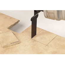 Pânză de fierăstrău sabie tăind o placă de piatră cu linii marcate și o decupare pătrată.