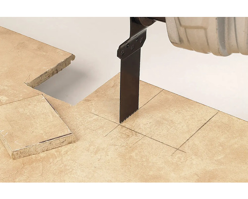 Pânză de fierăstrău sabie tăind o placă de piatră cu linii marcate și o decupare pătrată.