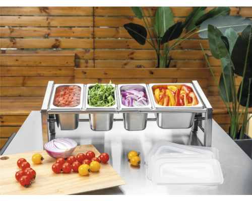 Stație de ingrediente din oțel inoxidabil cu patru recipiente Gastronorm umplute cu legume și sos pe o masă metalică cu tocător.