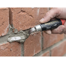 O persoană folosește o mistrie pentru rostuit Maurerlob pentru a aplica mortar între cărămizi roșii.