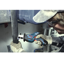 Meșter care taie o țeavă închisă la culoare cu un fierăstrău tip sabie cu acumulator Bosch Professional într-o zonă de lucru cu țevi metalice argintii.