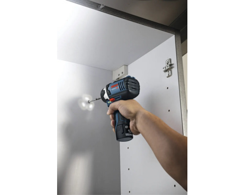 Mașină de înșurubat cu impact cu acumulator Bosch înșurubând un șurub într-un dulap alb.