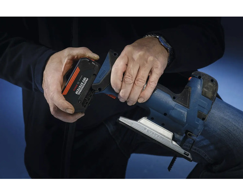 O persoană introduce un acumulator din sistemul Bosch Professional 18 volți într-un ferăstrău pendular.