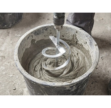 Un malaxor cu spirală amestecă mortar gri într-o găleată neagră de șantier.