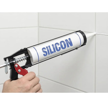 Aplicarea siliconului cu un pistol pentru cartușe pe un rost de faianță.