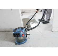 Aspirator cu acumulator pentru aspirare umedă și uscată Bosch Professional care aspiră apa de pe o podea de beton.