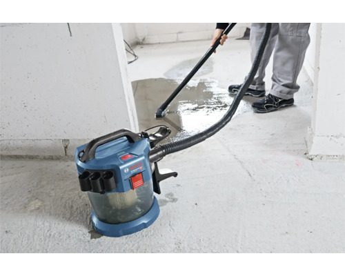 Aspirator cu acumulator pentru aspirare umedă și uscată Bosch Professional care aspiră apa de pe o podea de beton.