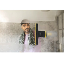Un aspirator electric de geamuri îndepărtează condensul de pe o suprafață de sticlă din baie, lăsând o urmă curată.
