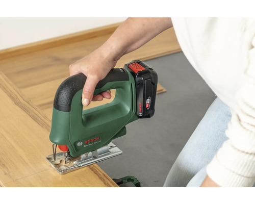 O persoană taie o bucată de parchet laminat cu un ferăstrău vertical cu acumulator Bosch EasySaw 18V-70.