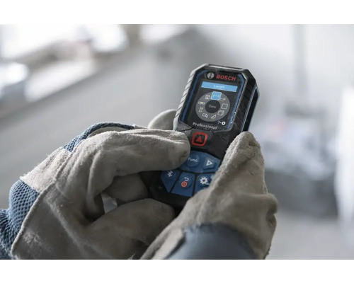 Telemetru cu laser Bosch Professional operat de mâini în mănuși de lucru, afișaj digital cu funcții de măsurare.