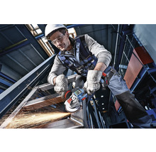 Meșter în echipament de protecție care prelucrează o structură de oțel cu un polizor unghiular cu acumulator sub formă de scântei.