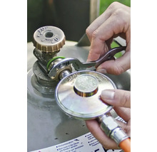 O persoană conectează un regulator de presiune la supapa unei butelii de gaz folosind o cheie pentru gaz CFH.