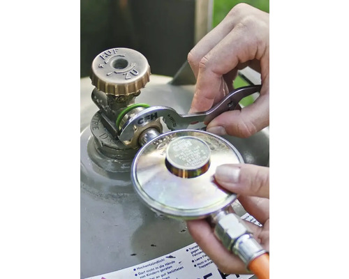 O persoană conectează un regulator de presiune la supapa unei butelii de gaz folosind o cheie pentru gaz CFH.