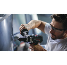 Meșter cu ochelari de protecție care folosește o mașină de găurit și înșurubat cu acumulator Bosch Professional pe o suprafață metalică.