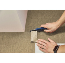 O persoană taie o pardoseală texturată din pâslă cu un cuțit utilitar.