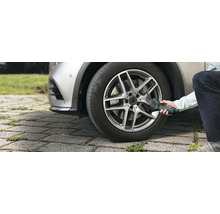 O persoană umflă o anvelopă auto în exterior cu ajutorul pompei de aer cu acumulator Bosch EasyPump.