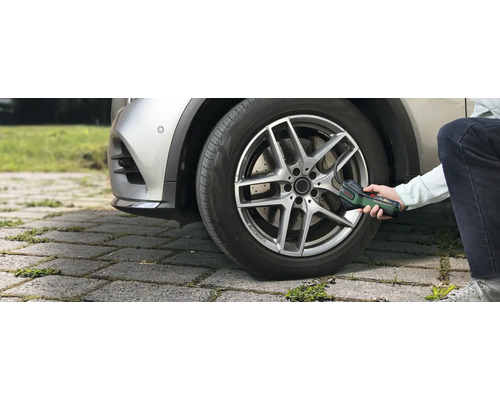 O persoană umflă o anvelopă auto în exterior cu ajutorul pompei de aer cu acumulator Bosch EasyPump.