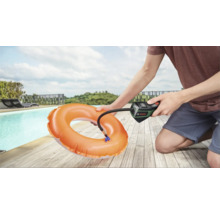 O persoană folosește o pompă de aer cu acumulator Bosch pentru a umfla un colac de înot portocaliu lângă o piscină.