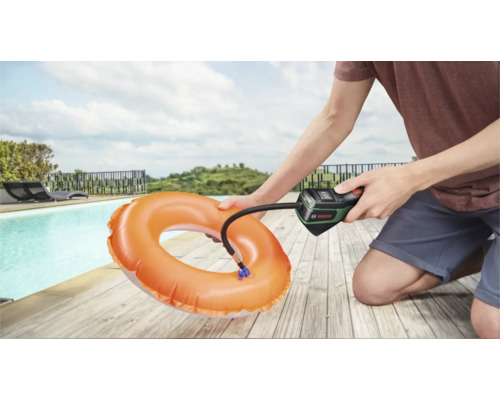 O persoană folosește o pompă de aer cu acumulator Bosch pentru a umfla un colac de înot portocaliu lângă o piscină.
