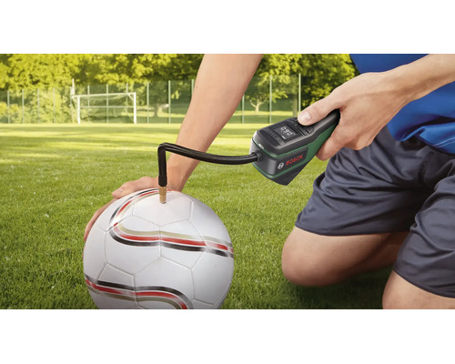 Pompă de aer cu acumulator Bosch umflând o minge de fotbal pe un teren cu iarbă.