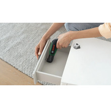 Șurubelniță cu acumulator Bosch IXO cu adaptor unghiular utilizată pentru înșurubarea unui sertar la o piesă de mobilier albă.