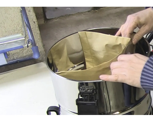 Introducerea unui sac de filtrare din hârtie în recipientul din oțel inoxidabil al unui aspirator umed-uscat.