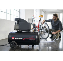 Compresor Einhell cu motor cu inducție într-un atelier luminos, un bărbat umflă o anvelopă de bicicletă.