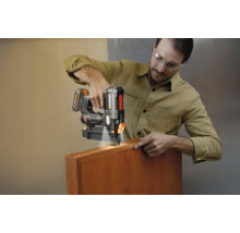 Bărbat care utilizează un pistol de cuie cu acumulator Worx cu lumină LED pe o piesă de lemn.