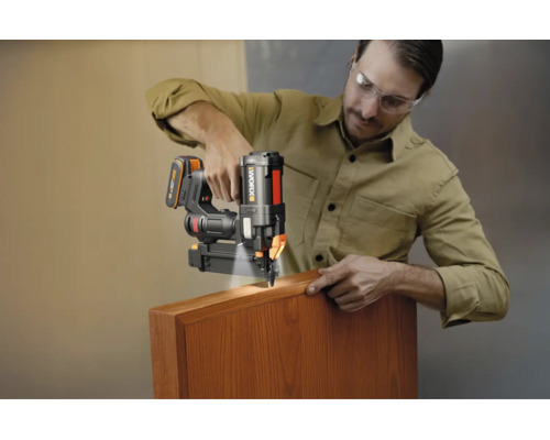 Bărbat care utilizează un pistol de cuie cu acumulator Worx cu lumină LED pe o piesă de lemn.
