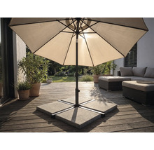Umbrelă de soare pe o terasă din lemn cu suport din plăci de beton, mobilier de grădină și plante într-un spațiu exterior luminos.