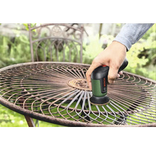O mână folosește un șlefuitor multifuncțional Bosch cu acumulator pentru a șlefui un scaun de grădină rotund din metal în exterior.