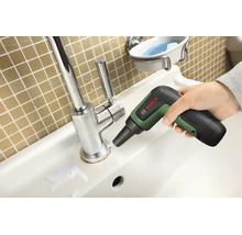 O mână utilizează o perie de curățare cu acumulator Bosch pentru a curăța baza unei baterii de chiuvetă cromate.