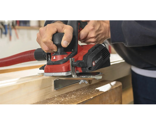 Rindea electrică Einhell pentru prelucrarea unei grinzi de lemn cu furtun de aspirare conectat într un atelier.