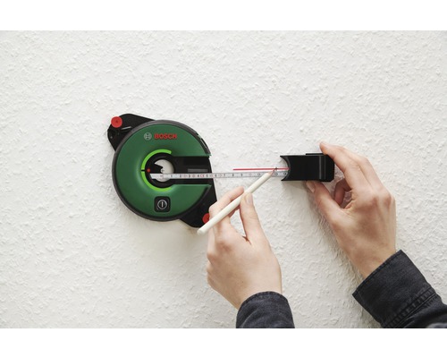 Logo Bosch. Persoană care lucrează cu un laser cu linii pentru aliniere pe un perete.