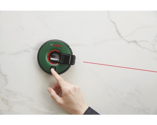Logo Bosch. O mână apasă butonul unei nivele laser cu linii, care proiectează o linie laser roșie.