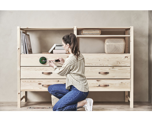 Femeie asamblând comodă din lemn cu rafturi folosind instrument digital de măsurare