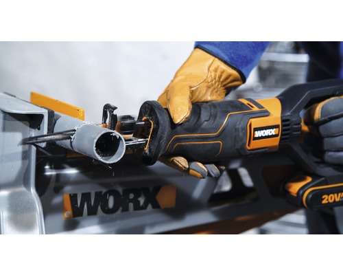 Fierăstrău electric cu acumulator tăind o țeavă pe o masă de lucru. Siglă Worx.