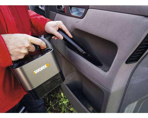 Persoană aspiră interiorul mașinii cu un aspirator fără fir marca Worx