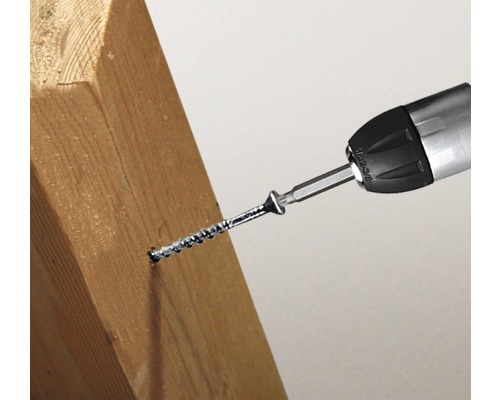 O șurubelniță înșurubează un șurub într-o bucată de lemn