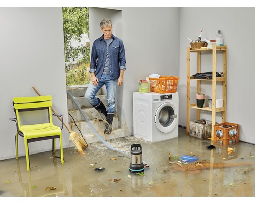 Subsol inundat cu pompă submersibilă în funcțiune, bărbat stând pe scări