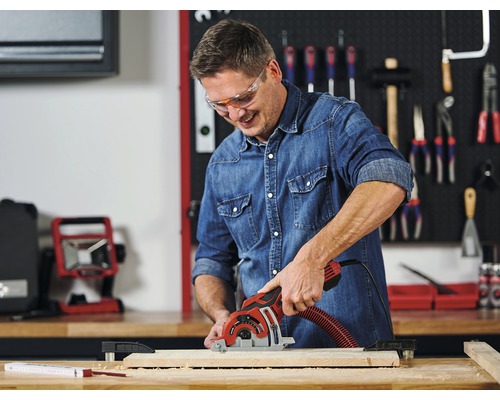 Bărbat taie o scândură de lemn cu un ferăstrău circular manual într-un atelier