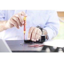 Artizan lucrând cu o șurubelniță la un dispozitiv electronic