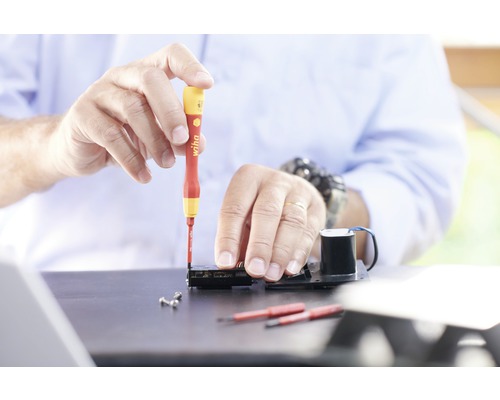 Artizan lucrând cu o șurubelniță la un dispozitiv electronic