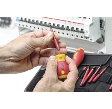 Bărbat schimbând un bit de șurubelniță Wiha în fața unei cutii de distribuție