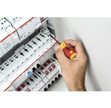 O mână folosește o șurubelniță pe o cutie de siguranțe cu componente ABB.