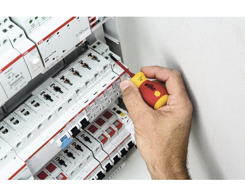 O mână folosește o șurubelniță pe o cutie de siguranțe cu componente ABB.
