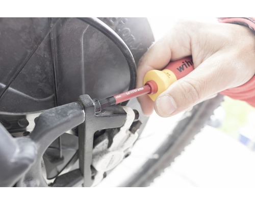 O persoană folosește o șurubelniță pe o bicicletă.