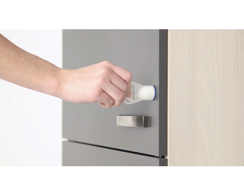 O mână atașează un dispozitiv de siguranță pentru copii la un sertar.